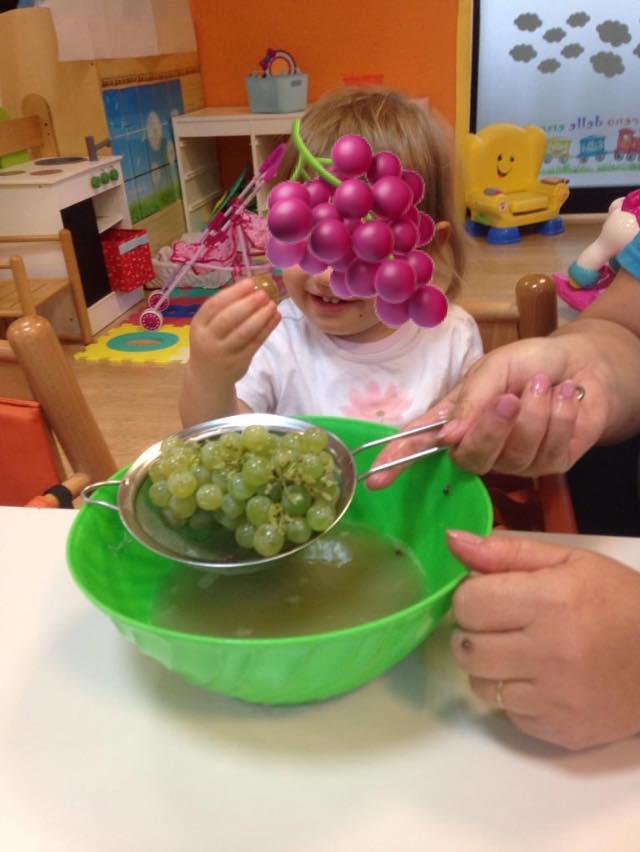 Bambina assaggia l'uva durante il laboratorio di cucina.